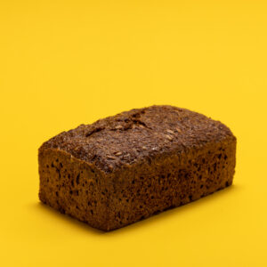 Ein dunkles Saftkorn-Brot auf einem gelben Hintergrund.